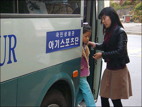 아기스포츠단 원생이 수업이 끝난 후 강사의 인도에 따라 귀가하기 위해 집 앞에서 내리고 있다. 